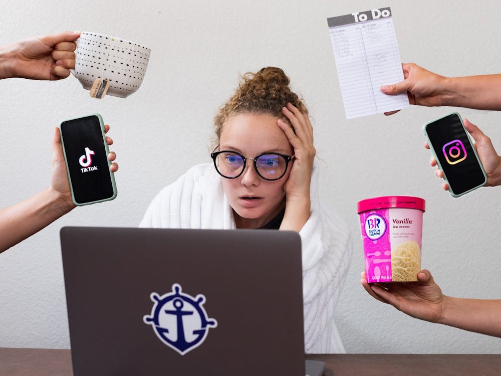 A UP student tries to focus on their online work in a distracting home environment. Photo Illustration by Molly Lowney