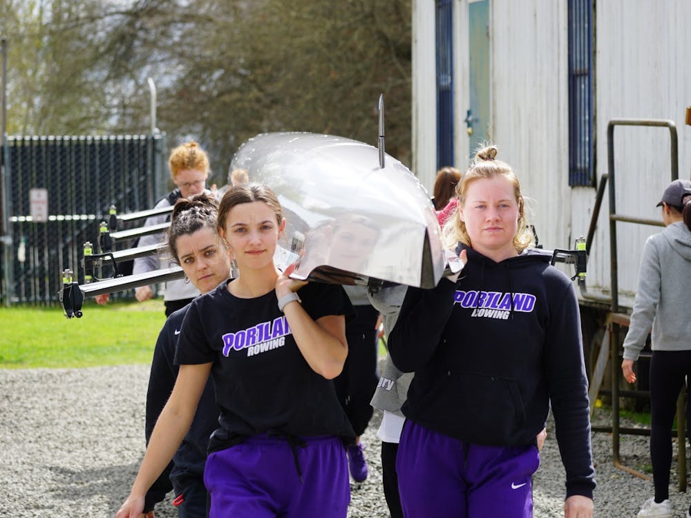 The team carrying a boat into the boathouse after winning two races at the Husky Classic.