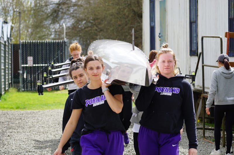 The team carrying a boat into the boathouse after winning two races at the Husky Classic.