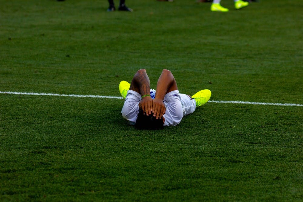 Senior midfielder Rey Ortiz lies down after the loss.