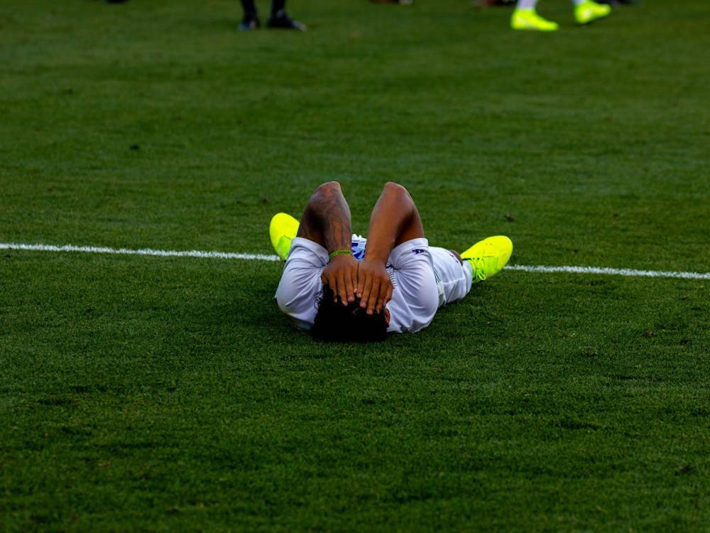 Senior midfielder Rey Ortiz lies down after the loss.