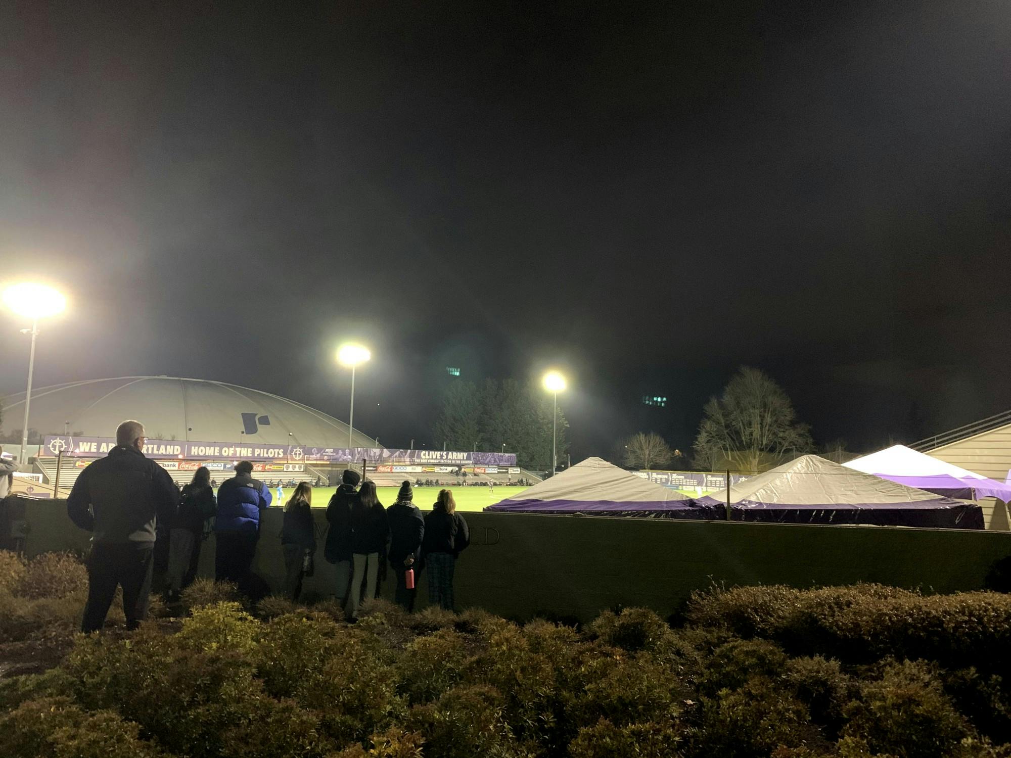 Students watch the men's soccer opener from outside the stadium. Spectators will not be allowed to watch athletic matches this season.