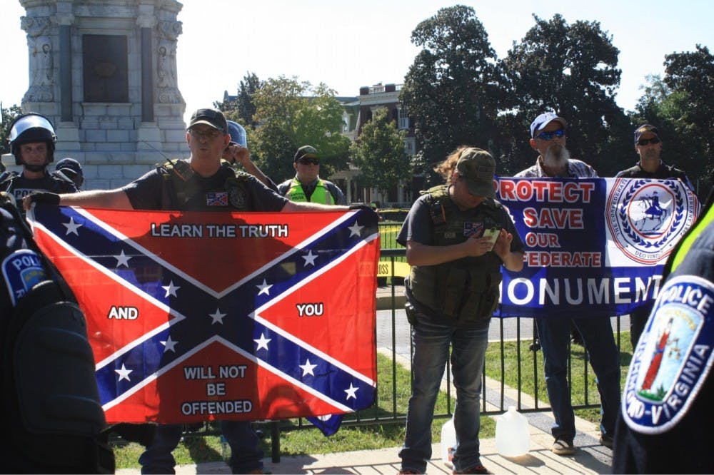 Members of a Tennessee-based Confederate group stand behind a police blockade in front of the Robert E. Lee statue.&nbsp;
