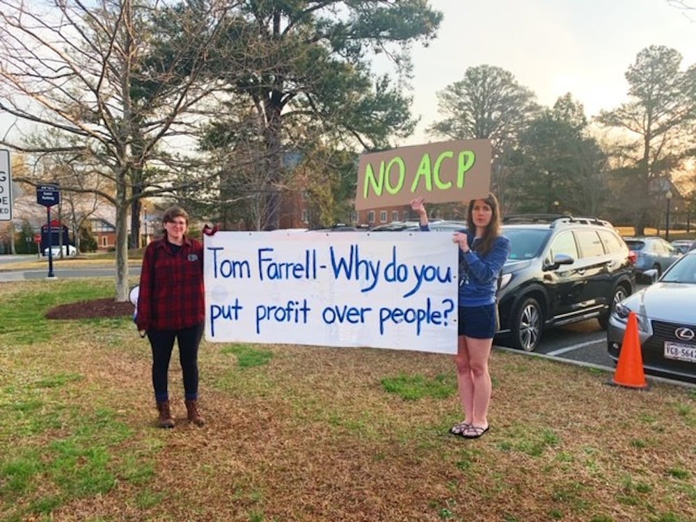 <p>Two protesters from The Virginia Student Environmental Coalition stand outside the Jepson Alumni Center.</p>