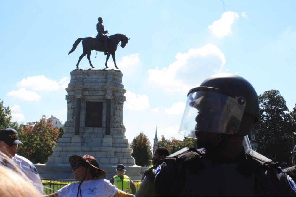 <p>A Richmond police officer stands guard in front of the Robert E. Lee statue on Saturday during a pro-Confederate rally on Monument Ave.&nbsp;</p>