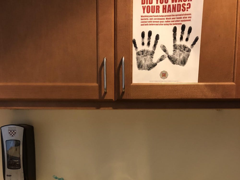 A sign reminds students to wash their hands above a sink.