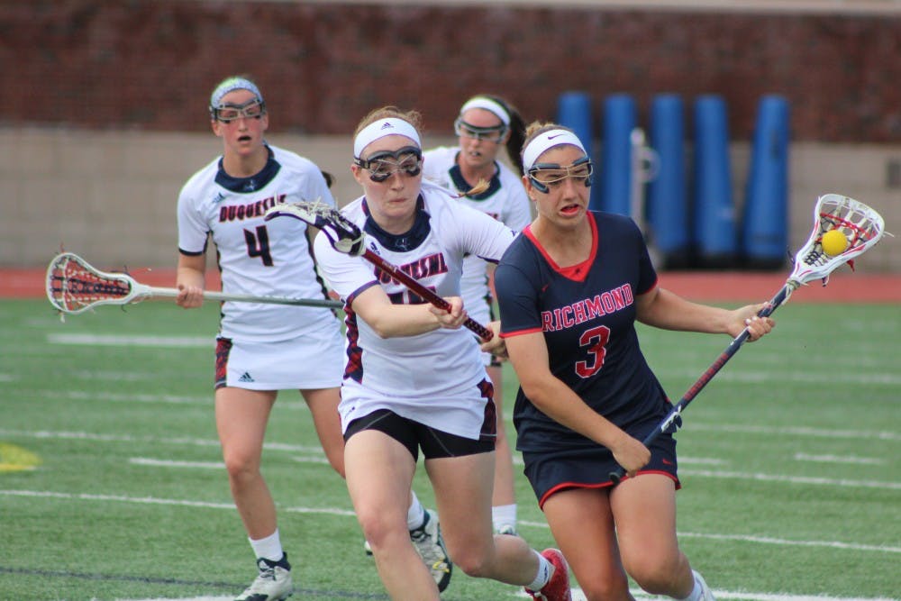 <p>Sam Geiersbach protects the ball against oncoming Duquesne defenders.</p>