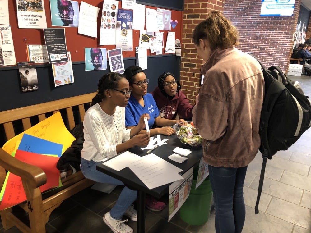A student approaches the Muslim Student Association table during Islam Awareness Week. From the left: Dowha Karar, Fatema Al Darii, Shamim Mohammed.