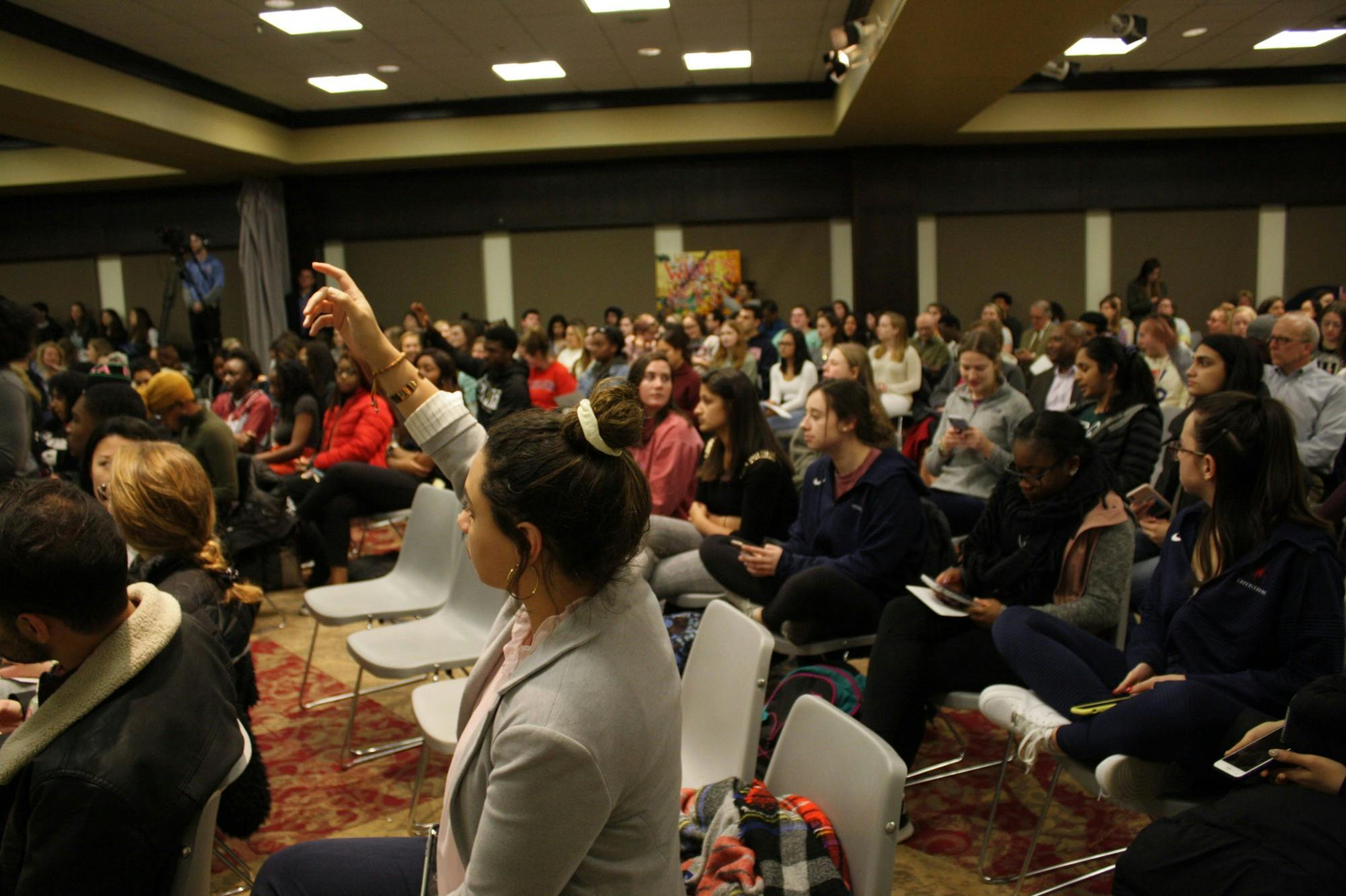 Students raise their hands to indicate that there are available seats near them before the start of the community meeting on Jan. 30.