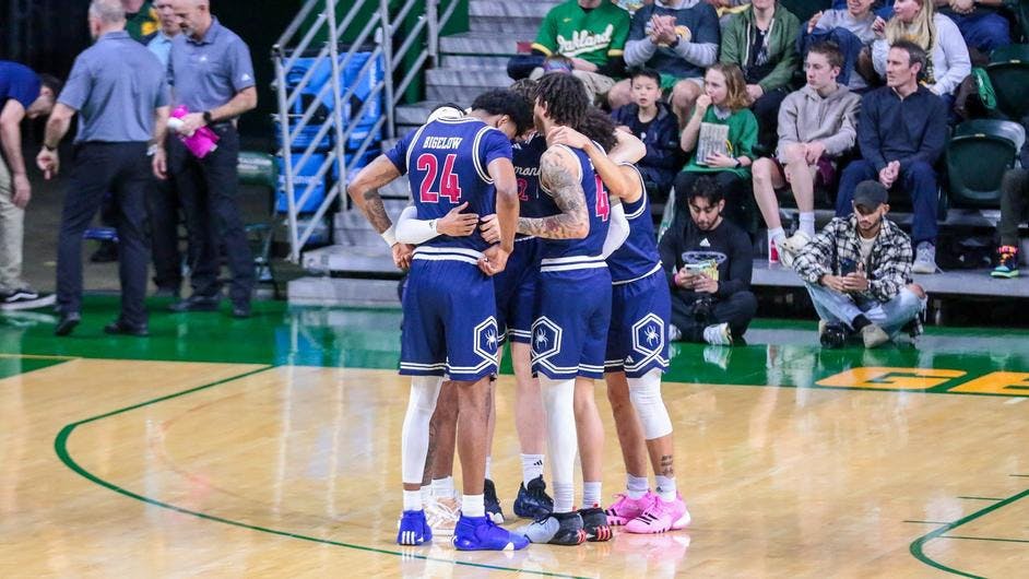 Graduate forward Isaiah Bigelow and senior guard Dji Bailey confer with teammates during the March 9 game against George Mason University. Courtesy of Richmond Athletics.