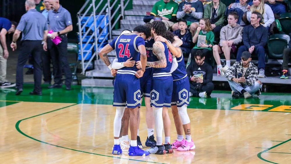 Graduate forward Isaiah Bigelow and senior guard Dji Bailey confer with teammates during the March 9 game against George Mason University. Courtesy of Richmond Athletics.