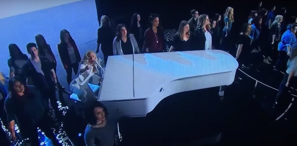 Lady Gaga, on the piano, is surrounded by sexual assault survivors&nbsp;as she performs Till it Happens to you at the 88th Academy Awards | Courtesy of YouTube
