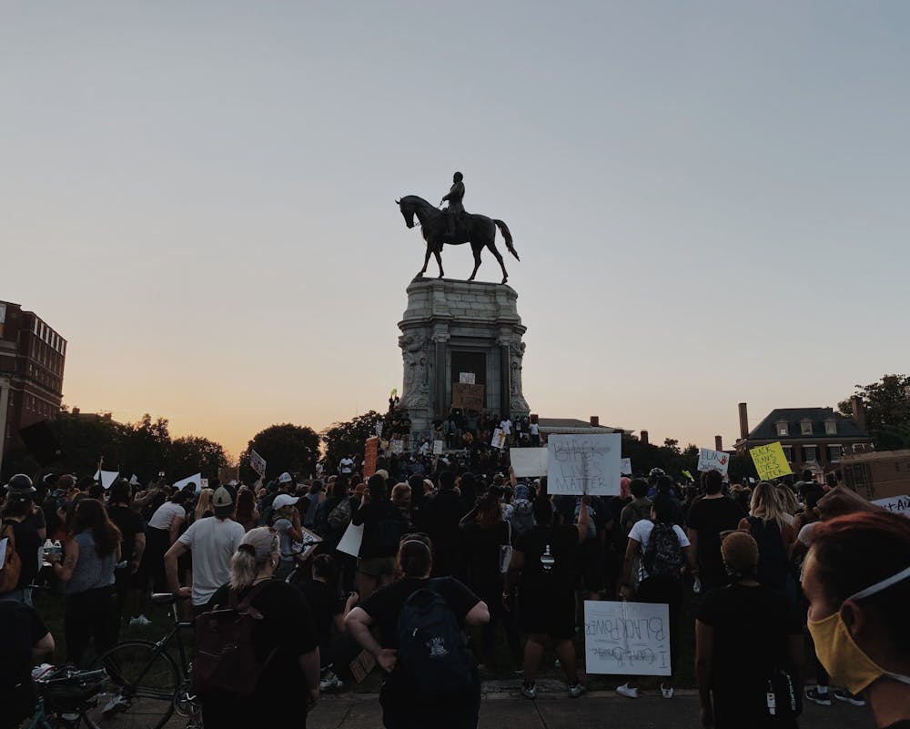 <p>Protesters gather on June 2 around the Robert E. Lee statue on Monument Avenue, where demonstrators stand on the statue, which is covered with graffiti.&nbsp;</p>
