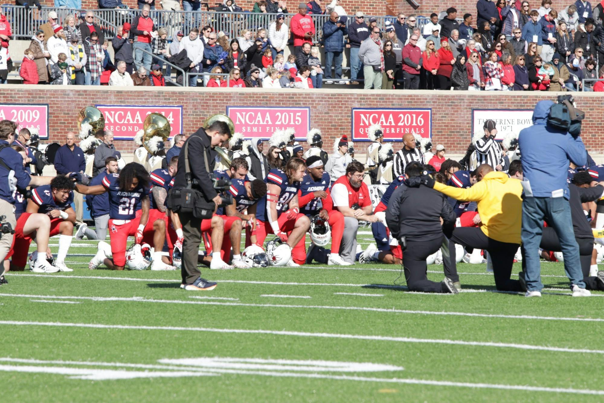 Players kneel in a moment of silence at the E. Claiborne Robins Stadium on Nov. 19 for the victims of the UVA shooting.