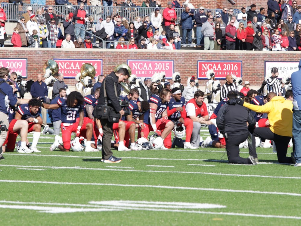 Players kneel in a moment of silence at the E. Claiborne Robins Stadium on Nov. 19 for the victims of the UVA shooting.