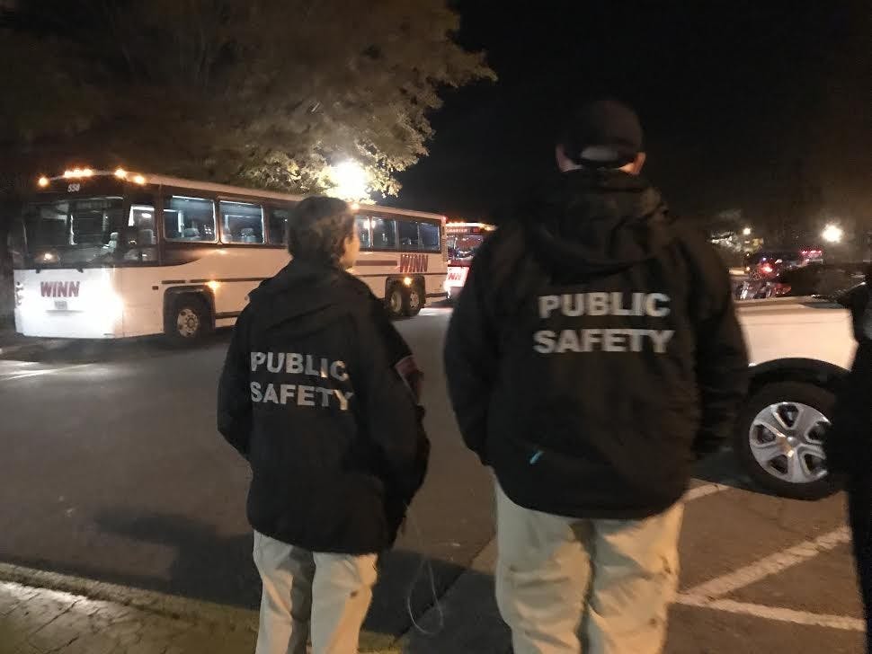 Bright and Linardo look on as buses carrying students from a social pull back onto campus.