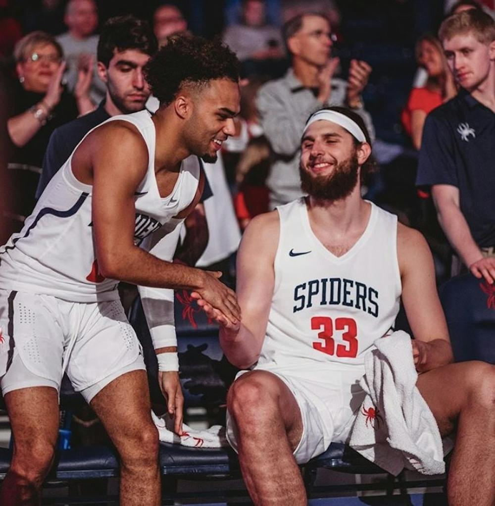 <p>Jacob Gilyard gives forward Grant Golden a pregame handshake as his name is announced during the starting lineups at the Robins Center. <em>Photo courtesy of Richmond Athletics</em></p>
