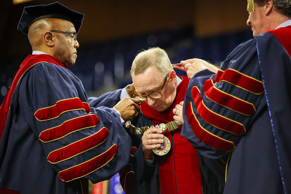 <p>Chancellor Richard Morrill and former UR presidents Edward Ayers and Ronald Crutcher present UR President Kevin Hallock with the mace, university seal and chain of office at his inauguration ceremony on April 8 at the Robins Center.</p>