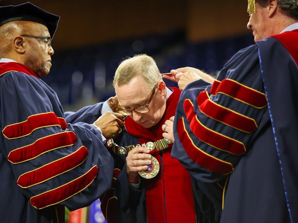 Chancellor Richard Morrill and former UR presidents Edward Ayers and Ronald Crutcher present UR President Kevin Hallock with the mace, university seal and chain of office at his inauguration ceremony on April 8 at the Robins Center.
