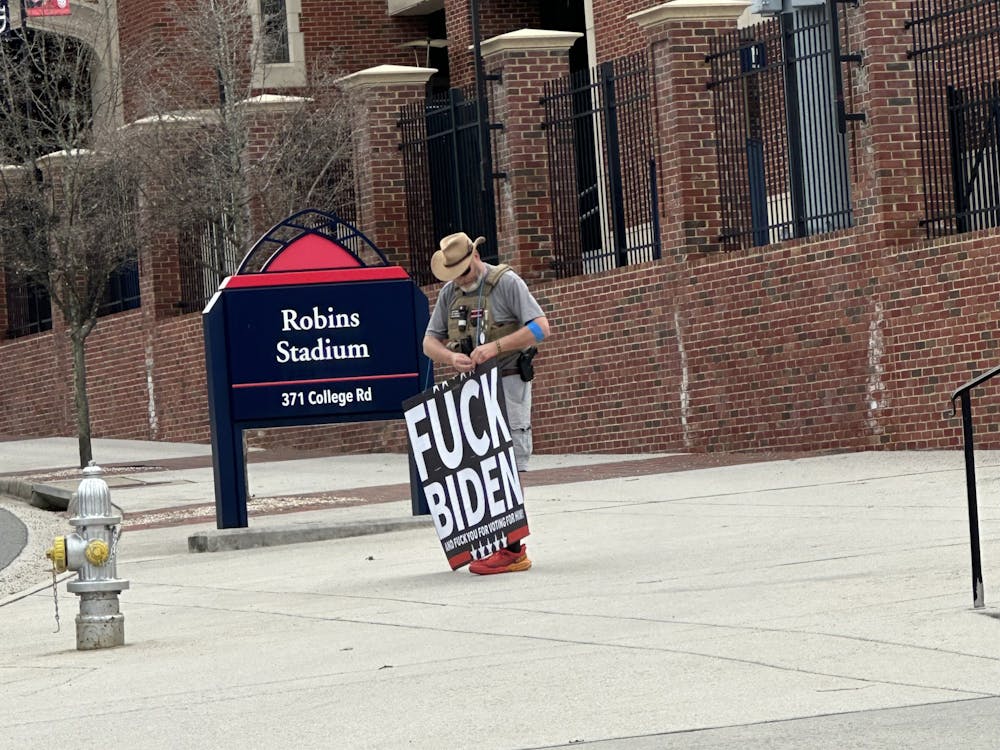 Ron Hedlund, armed and holding a poster reading "Fuck Biden", stands outside the Robins Center Jan. 10.&nbsp;