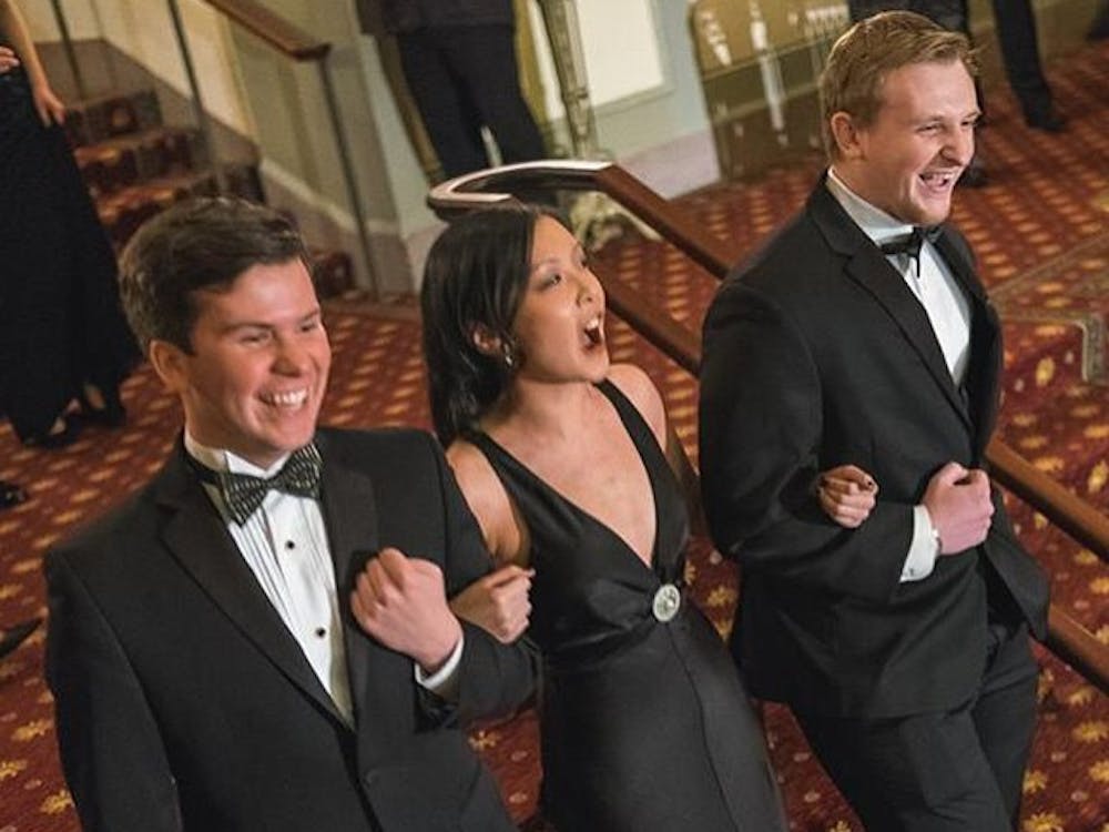 Junior Regina Zhong walking with her escorts Kevin Cloyes (left) and Chris Okrasinski (right) at Ring Dance in 2015. | Photo courtesy of Regina Zhong. 