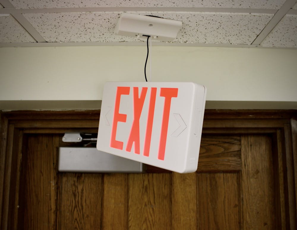 A broken exit sign dangles from the ceiling on the first floor of South Court. 