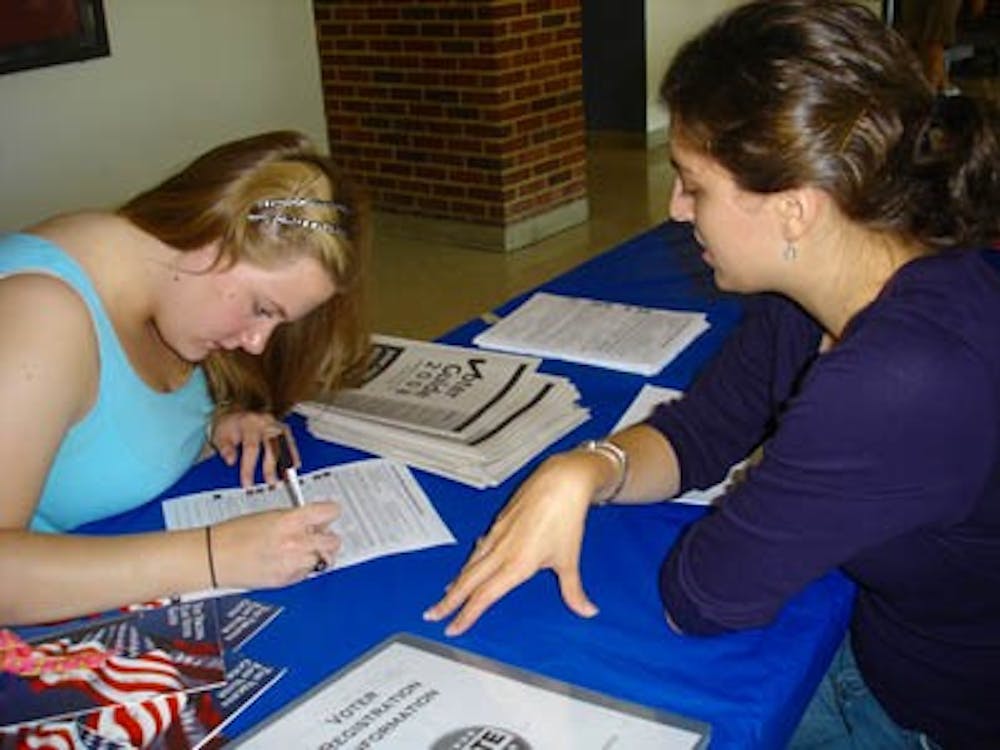 Colleen Szurkowski fills out a voter registration form with help from Amanda Kleintop.