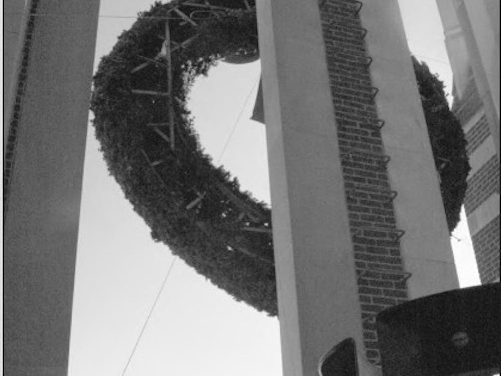 Robert Naracon, an university electrician, helps hang a wreath on Boatwright tower in 2005. Photo originally published in The Collegian in 2005.&nbsp;