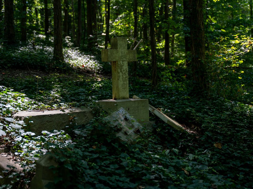 As nature reclaims the land, a century-old cross stands alone among the ruins of several forgotten graves at the Evergreen Cemetery on August 31, 2019. 