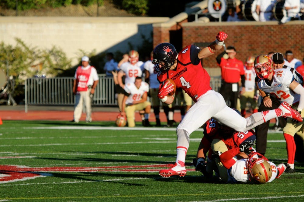<p>Seth Fisher jumps over players on his way to a long run down the left side of the field. Fisher led the Spiders in rushing with 87 yards against VMI. Photo by Rayna Mohrmann.</p>
