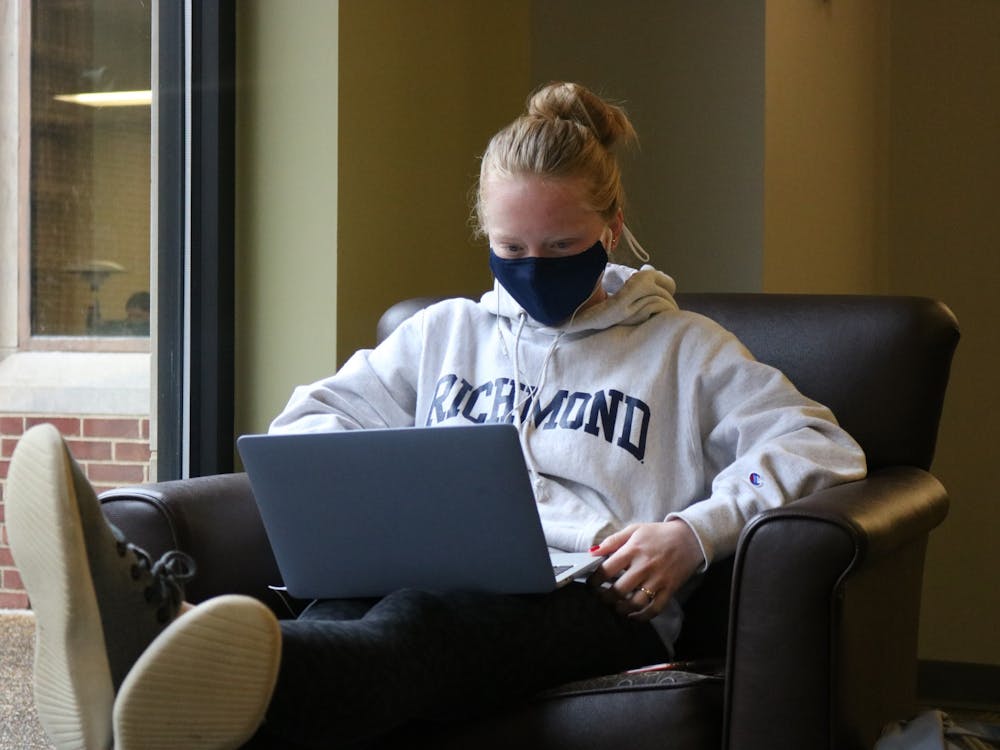 A masked student sits with a laptop in Boatwright Memorial Library.