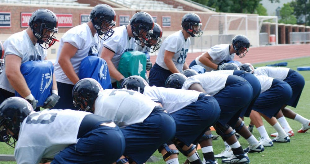 Schmitz, standing left of center with a blue pad, works on blocking drills with his teammates during training camp his sophomore year. All photos courtesy of Richmond Athletics.&nbsp;