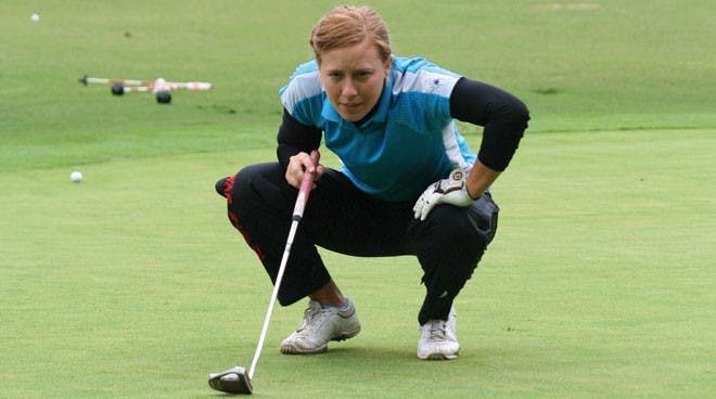 Senior Lauren Folgosa lines up a putt during practice at the Spider Golf Facility.