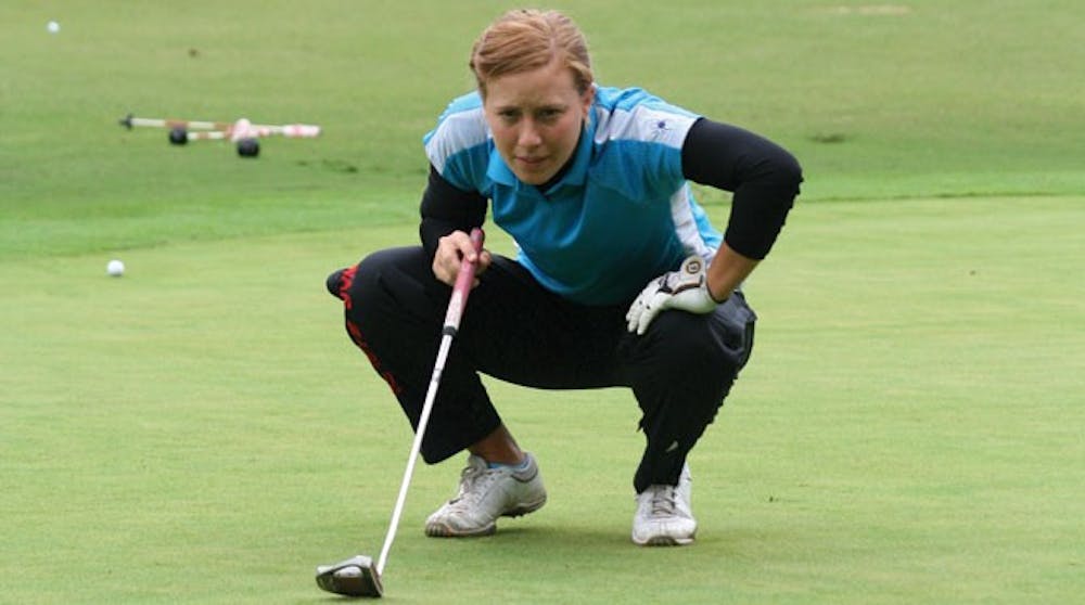 Senior Lauren Folgosa lines up a putt during practice at the Spider Golf Facility.