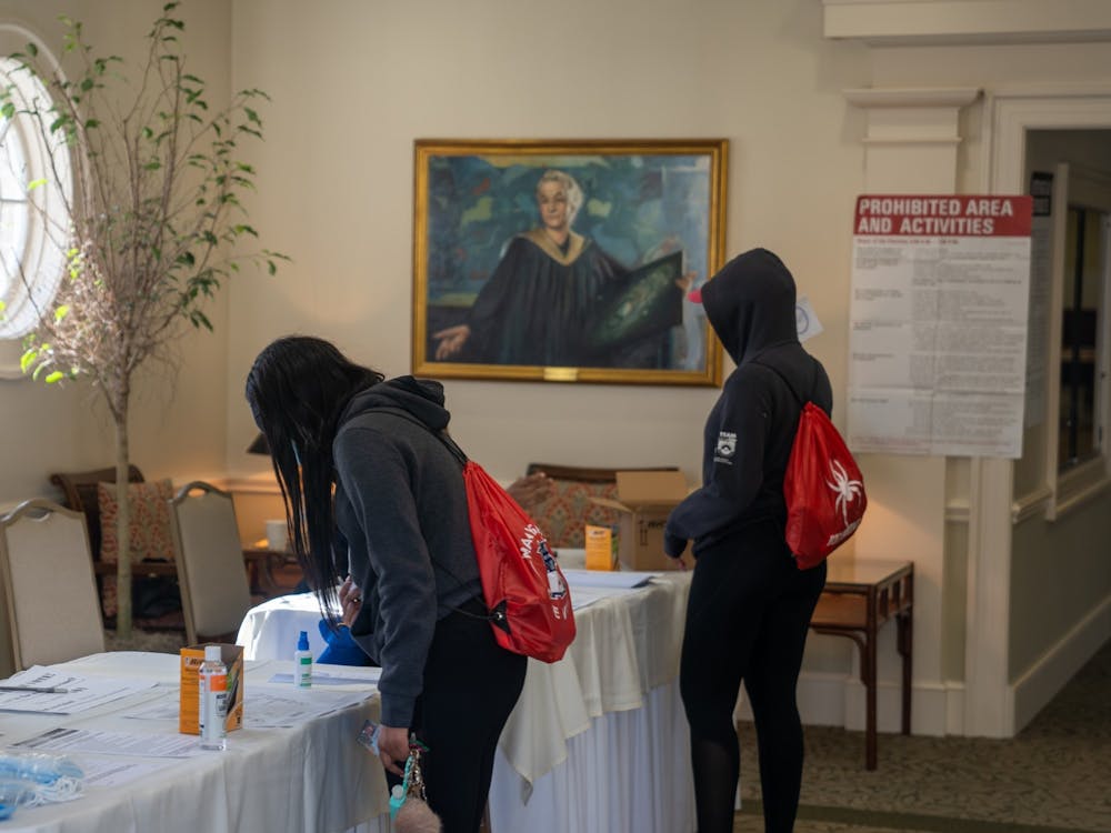 Two student-athletes sign in to vote among hand sanitizer, masks and COVID.