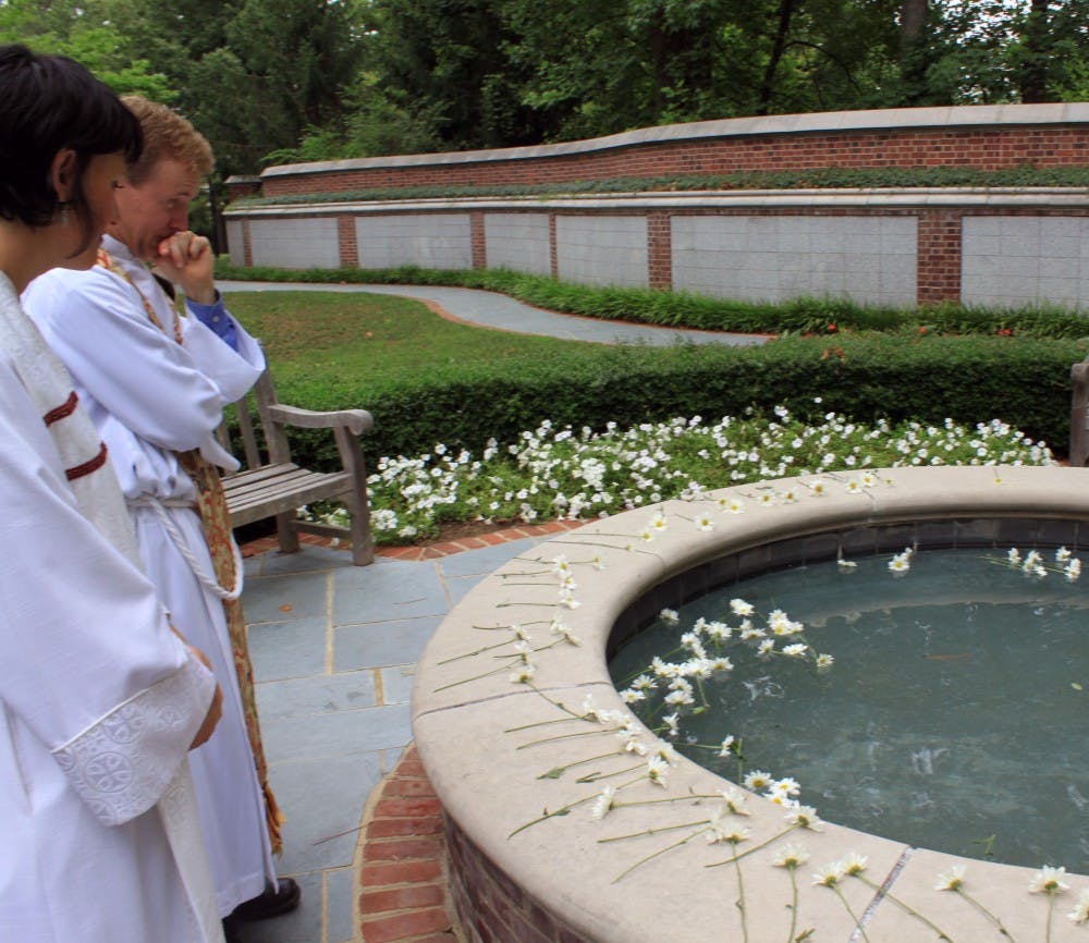 Rev. Craig Kocher, left, and associate chaplain Kate O'Dwyer Randall stand and reflect in front of a memorial pool filled with daisies in memory of Jamie and Paige Malone at the Cannon Memorial Chapel at the University of Richmond.