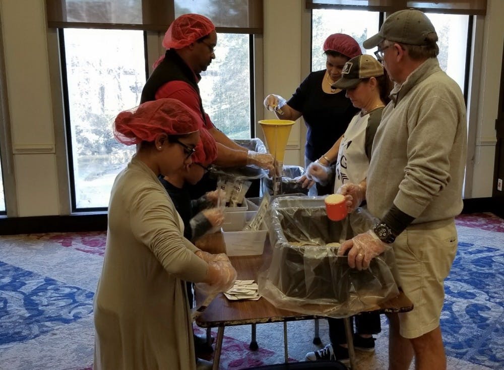 <p>Melania Lambert,11 (bottom left), Benjamin Lambert IV, 7, Mark Parson, Rhonda Parson, Laura Grivetti and Don Grivetti prepare meal bags during the Rise Against Hunger meal packaging event.</p>