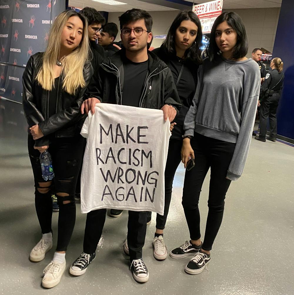 Student protesters pose with a sign after leaving the arena during the University of Richmond men's basketball game on Saturday, Jan. 25, 2020. Janis Lee, junior (left); Nasir Aziz, senior; Aamina Ahmed, junior; Aleena Ahmed, first-year.&nbsp;