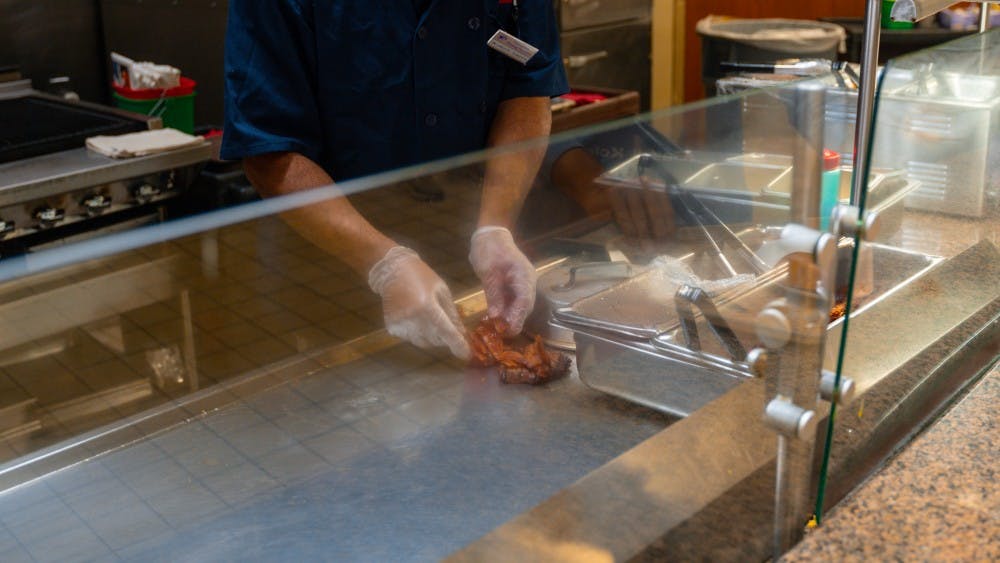 <p>A dining hall employee prepares a hamburger. All-beef burger patties returned to the dining hall after a four-month hiatus.&nbsp;</p>