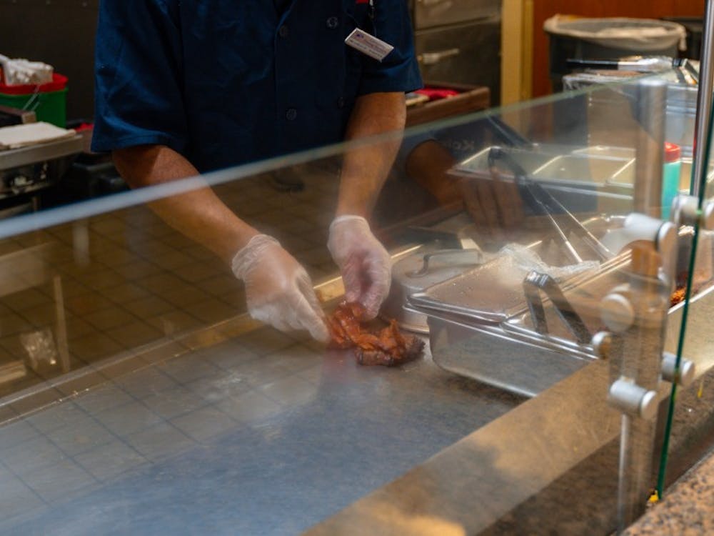 A dining hall employee prepares a hamburger. All-beef burger patties returned to the dining hall after a four-month hiatus.&nbsp;