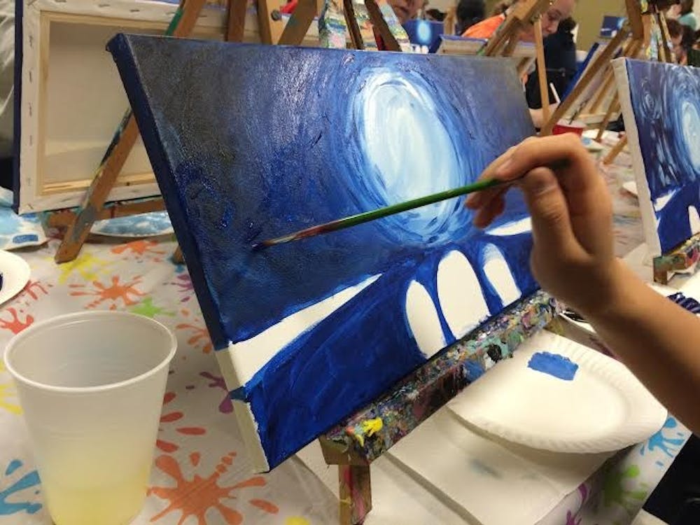 <p>A student adds to her work in progress during the Spider Board painting class.</p>