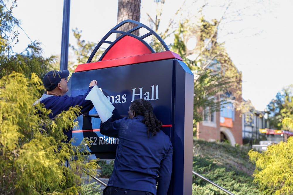 <p>Workers cover up the sign for the building previously-named Thomas Hall on March 28.</p>