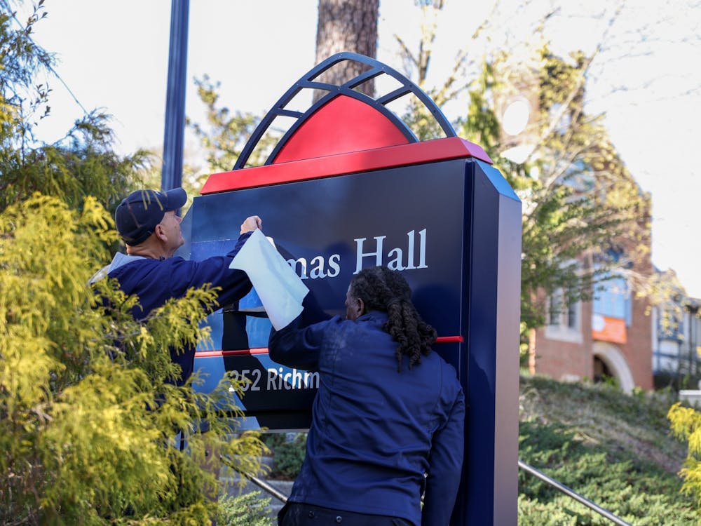 Workers cover up the sign for the building previously-named Thomas Hall on March 28.
