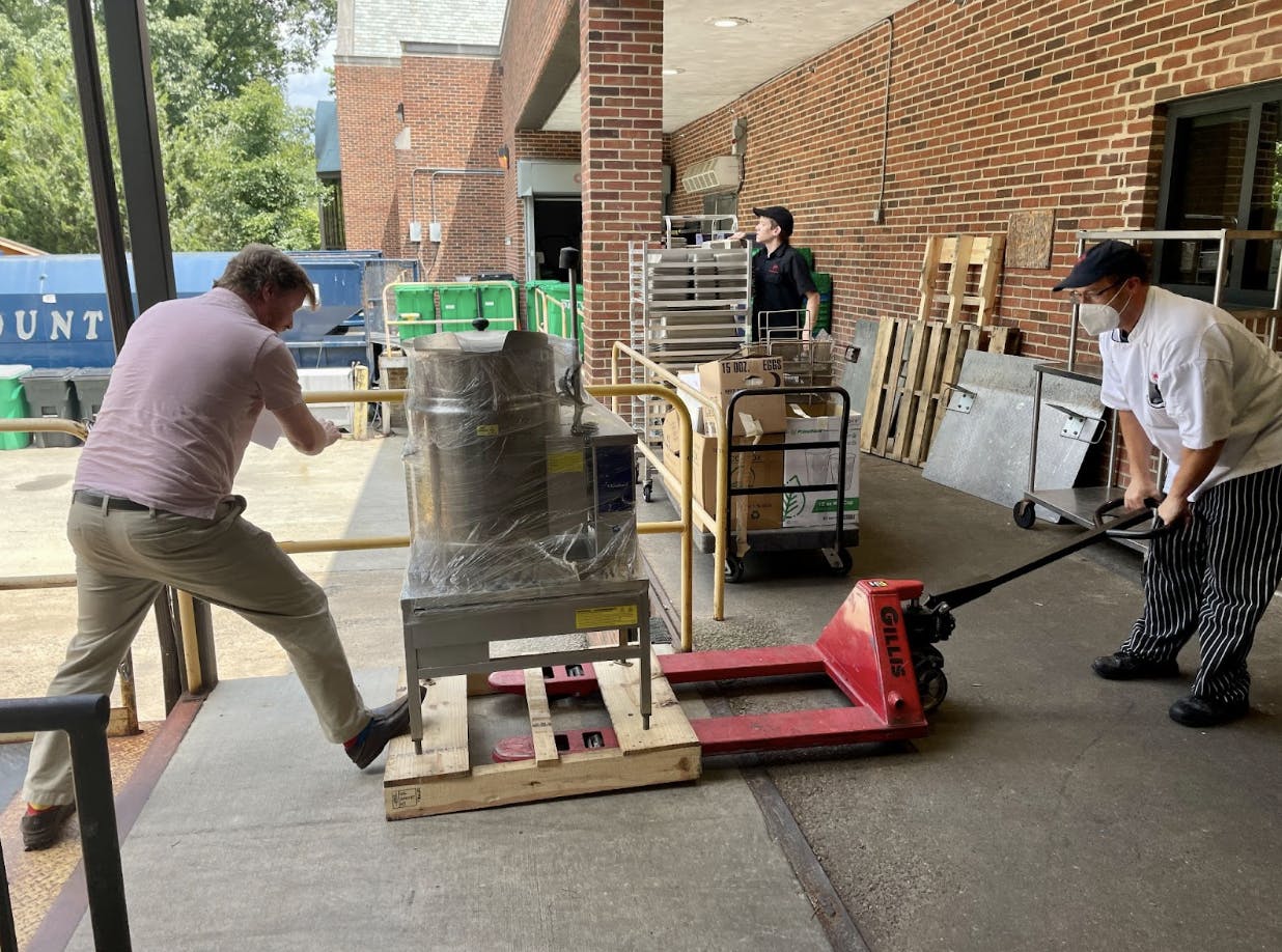Josh Wroniewicz, business office director, and Andrew Kerscher, chef de cuisine, load equipment to donate to CARITAS. Photo courtesy of Kirsten McKinney.