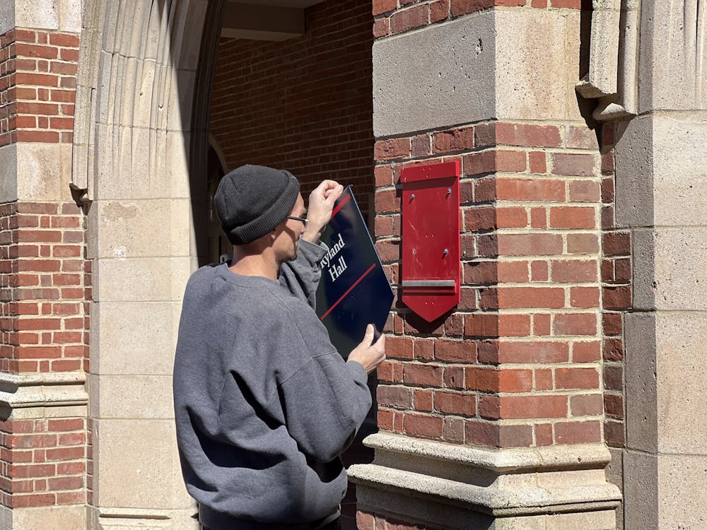 <p>Workers remove a name-plate from the building formerly known as Ryland Hall on March 28.</p>