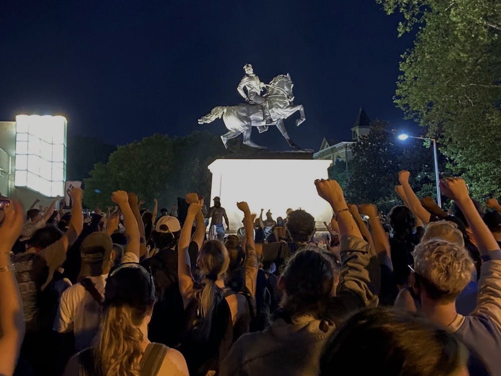 Protesters stand in front of the "Rumors of War" statue created by Kehinde Wiley at 11 p.m. on June 3, raising their fists in solidarity.&nbsp;