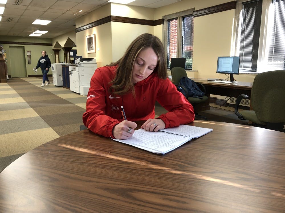 First-year swimmer Jenna Carastro works on homework at Boatwright Memorial Library. 