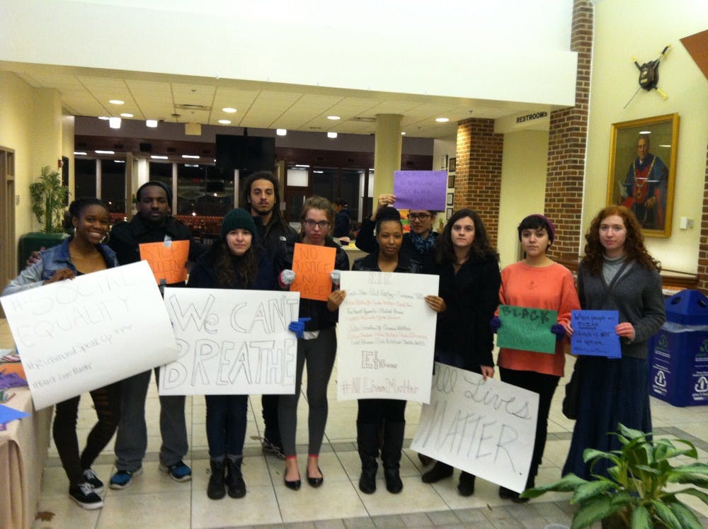 <p>Protestors calling for social justice hold posters in the Heilman Dining Center at Sunday night's demonstration. </p>