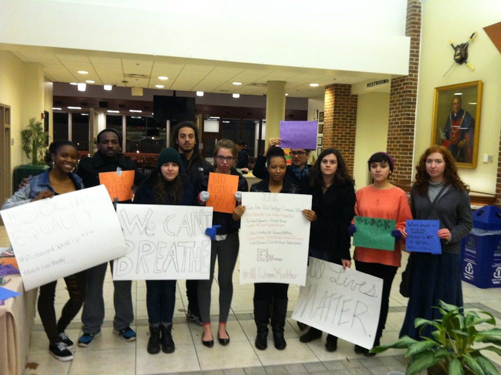 Protestors calling for social justice hold posters in the Heilman Dining Center at Sunday night's demonstration. 