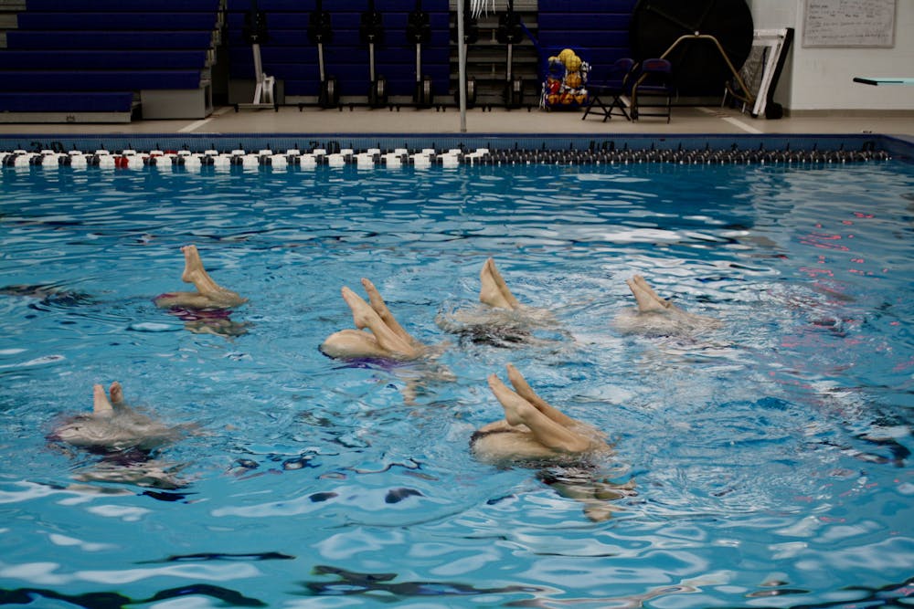 Synchronized swimmers preparing to do a ballet leg move.